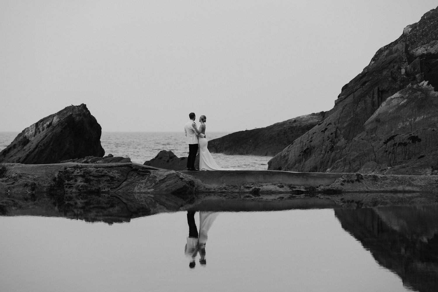 Bride and Groom on rocks on beach during sunset at tunnels beach wedding venue in north Devon