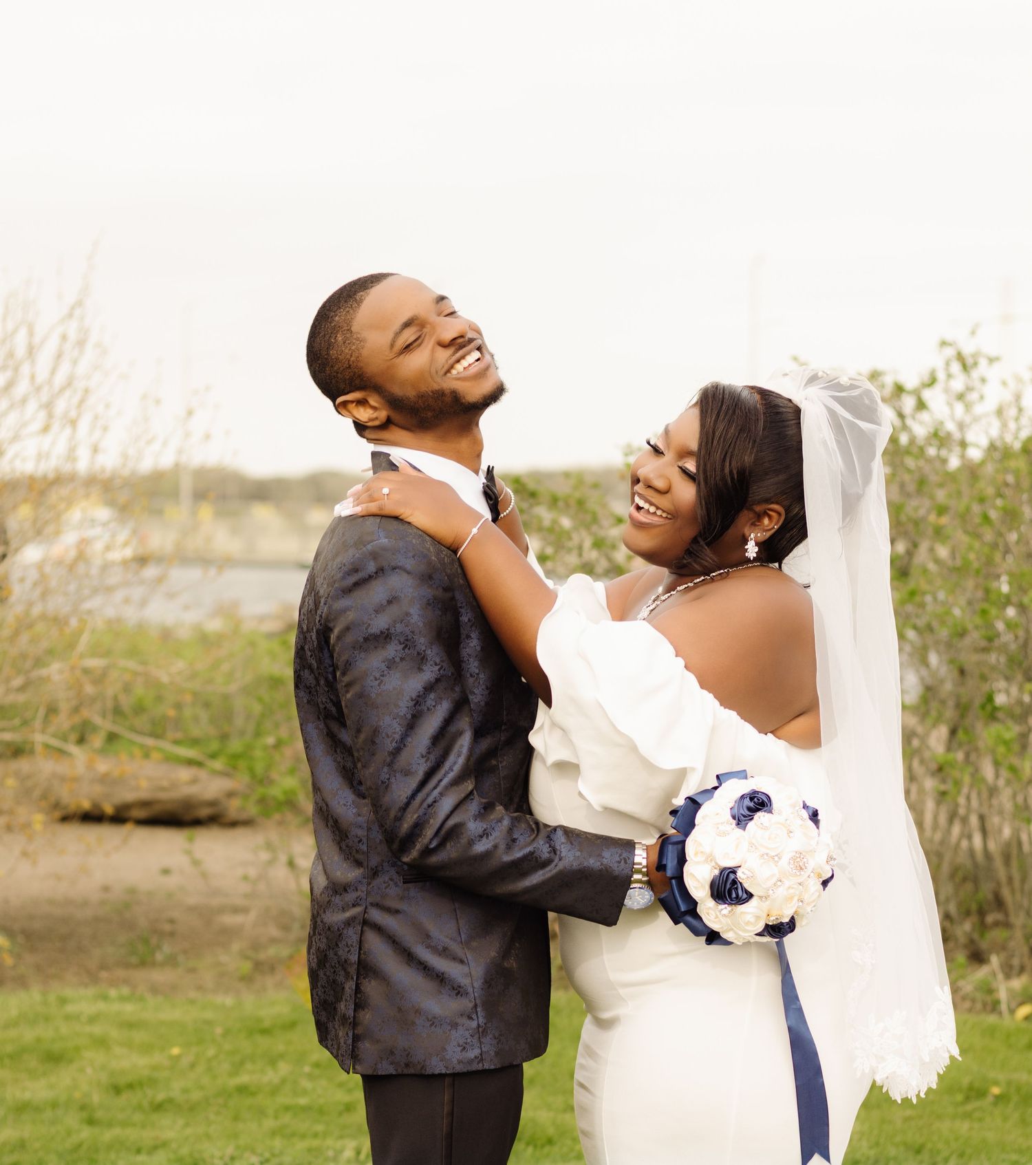 A joyful wedding couple laughs together while holding a soccer ball bouquet on their special day.