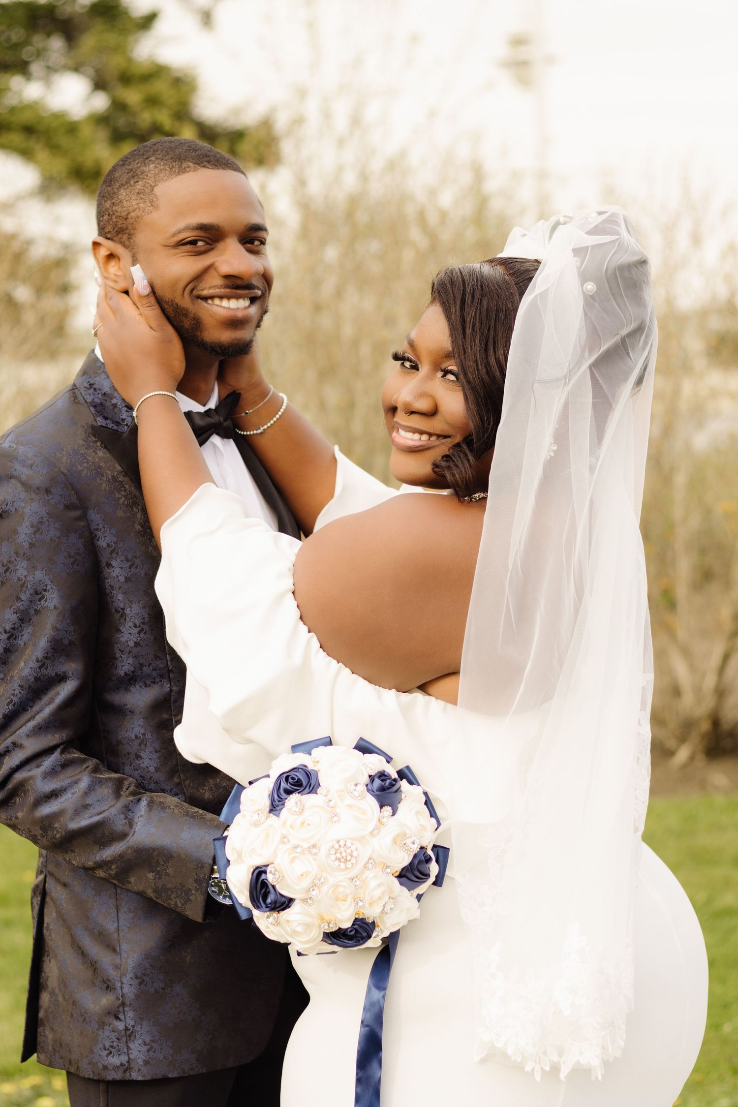 A romantic wedding photo outdoors with white and navy florals captures a tender moment between newlyweds.