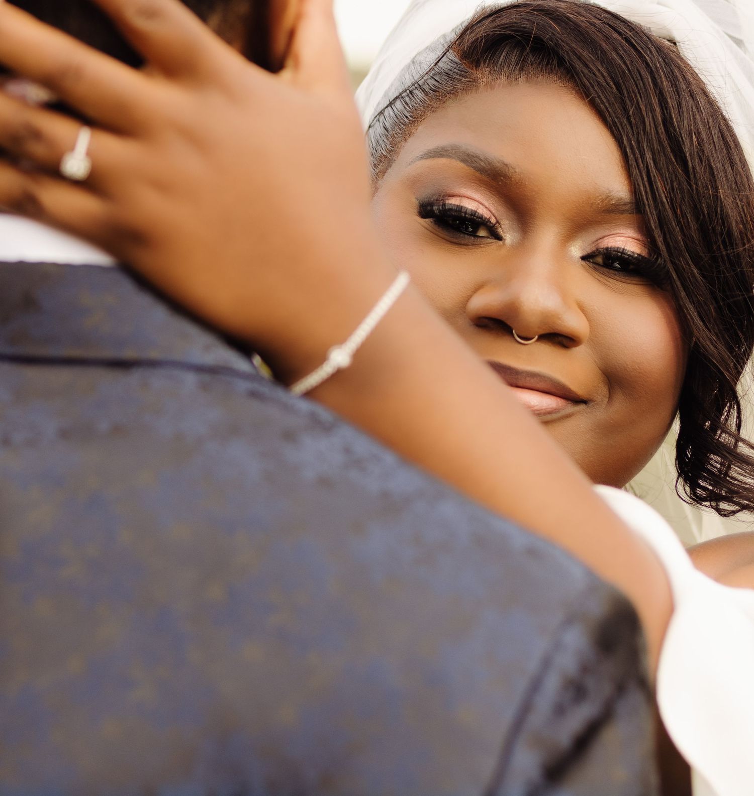 Close-up portrait of someone smiling warmly while wearing makeup, with soft lighting creating a romantic mood.