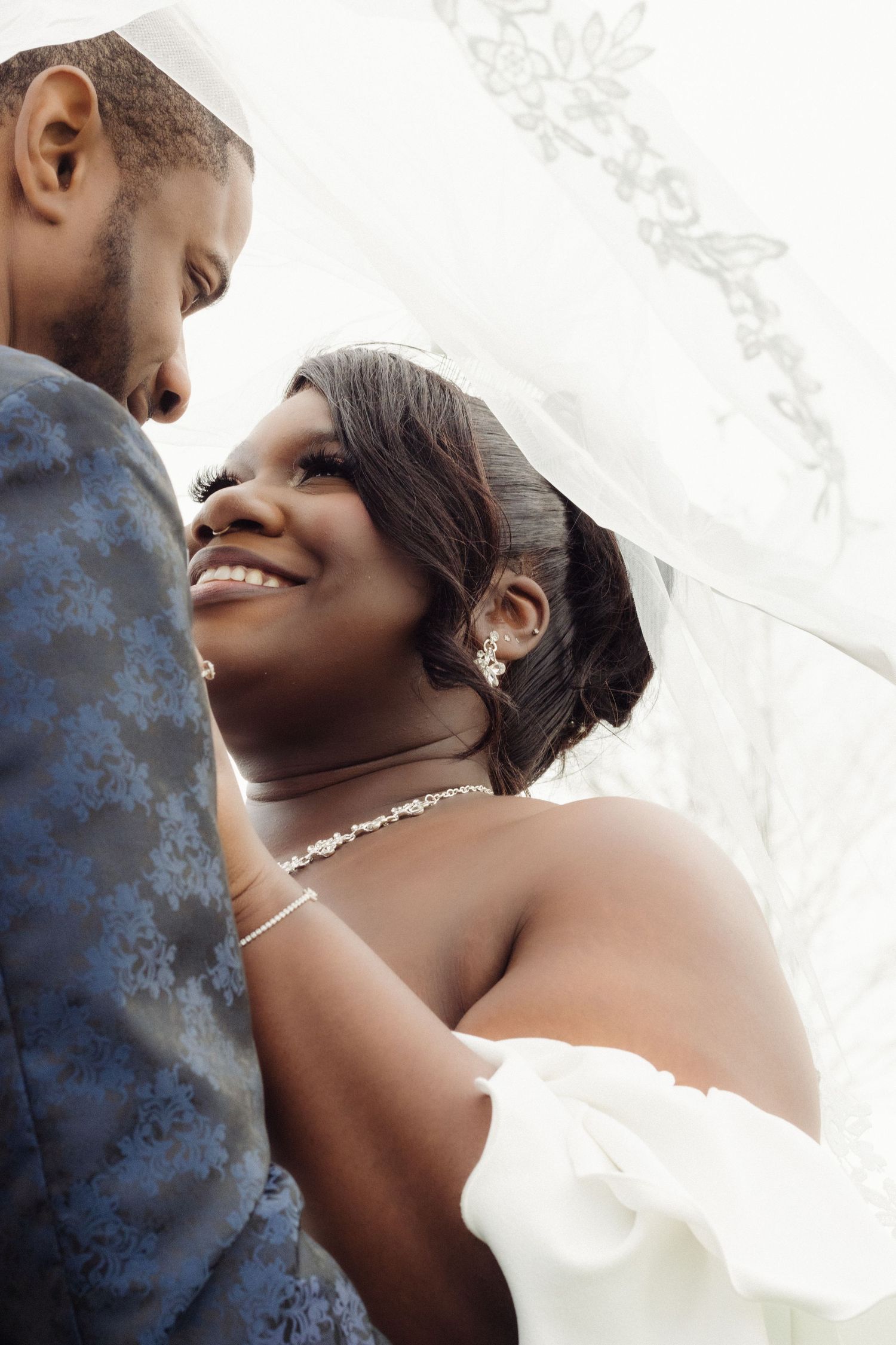 A romantic wedding moment between a couple in elegant attire, with the bride wearing delicate jewelry.