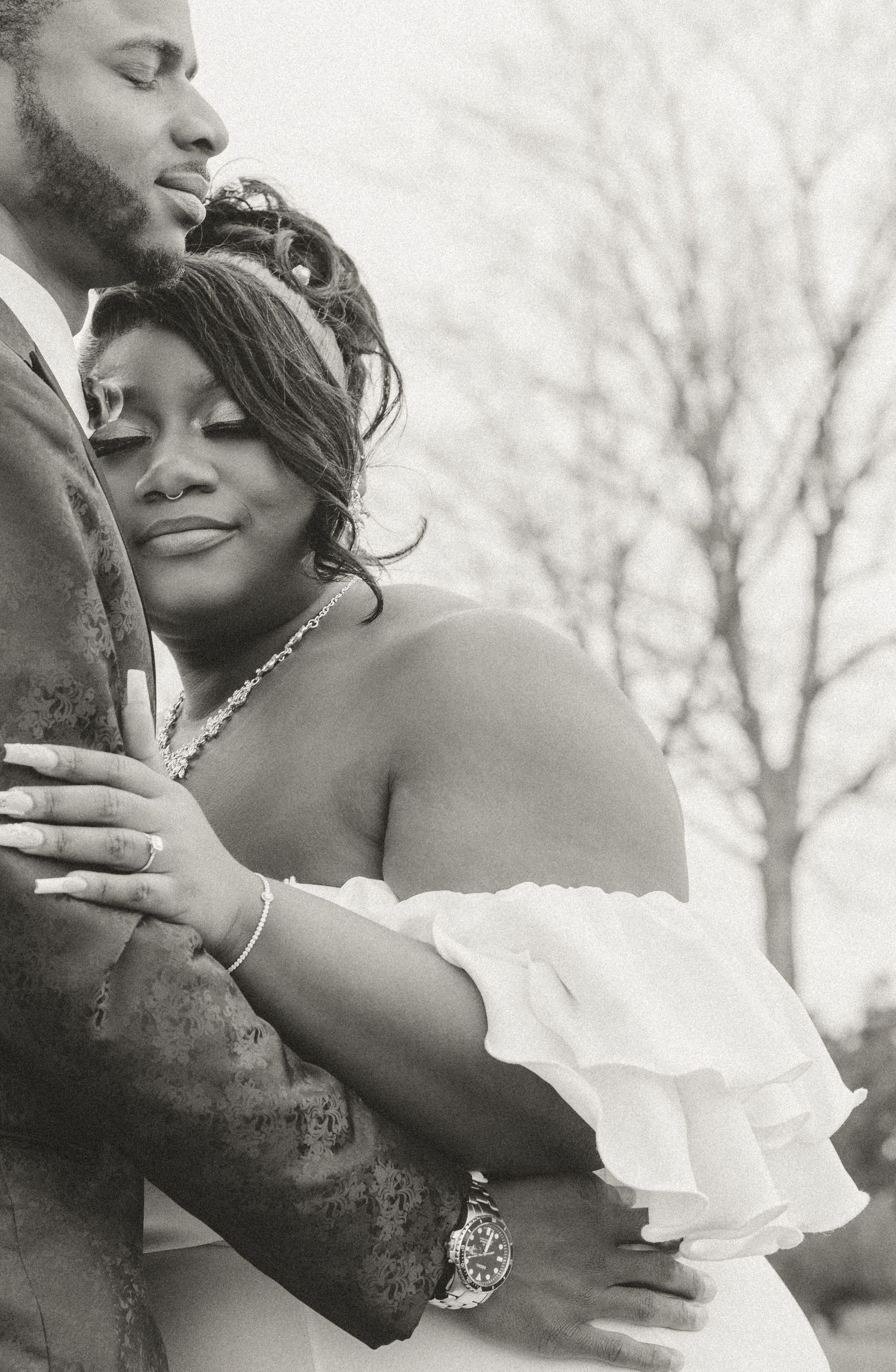 Intimate black and white portrait of newlyweds embracing during outdoor wedding photoshoot.