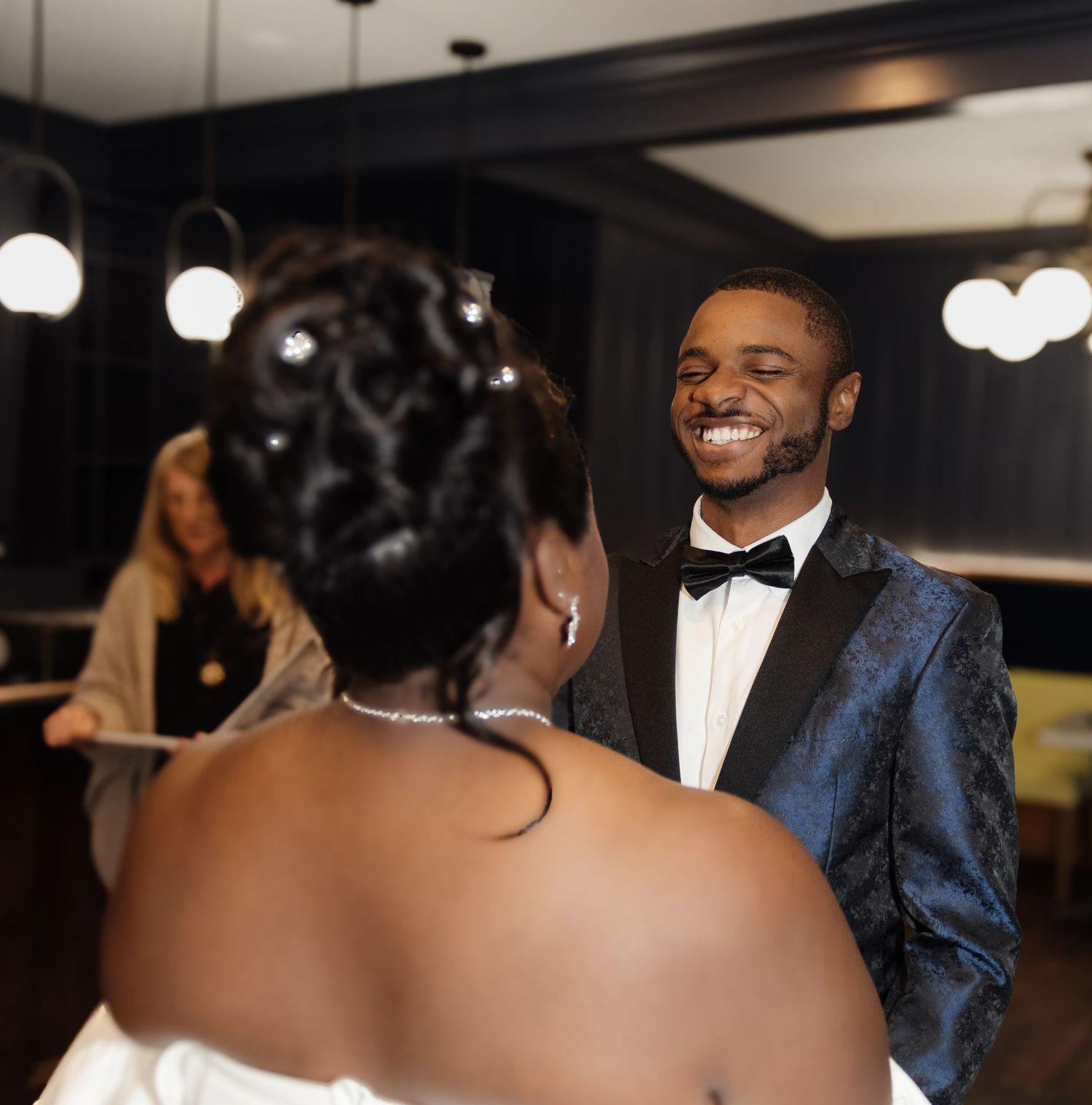 Couple shares joyful moment during wedding as groom in blue tuxedo beams with happiness.