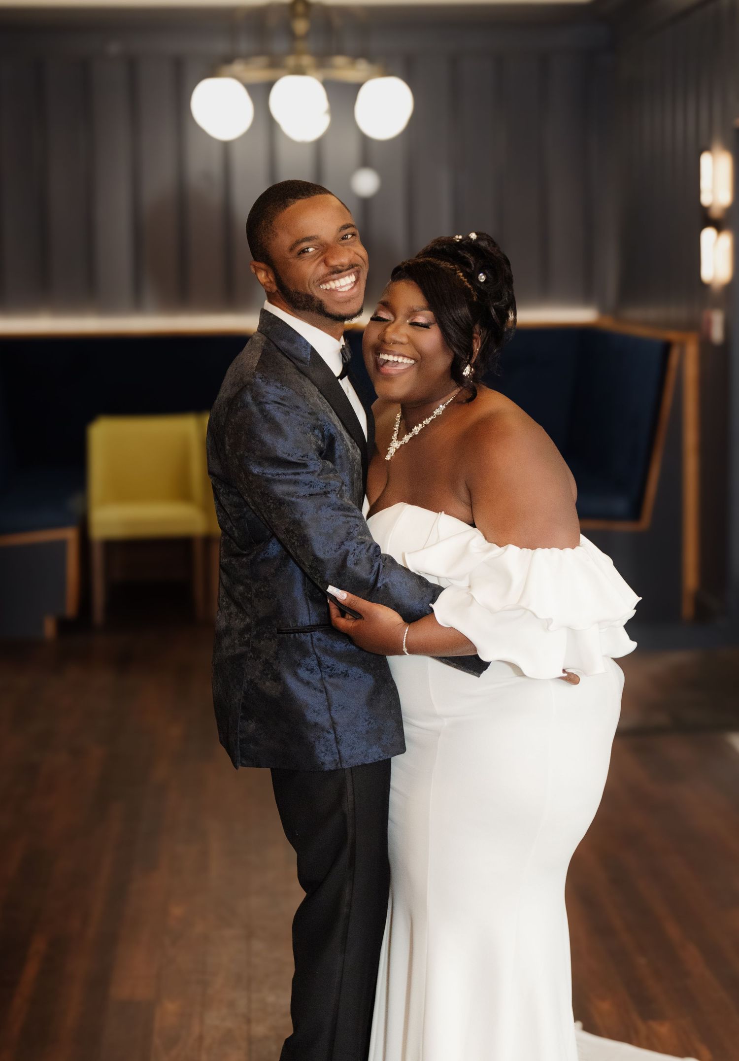 Joyful couple dancing and laughing together during their wedding reception in an indoor venue.