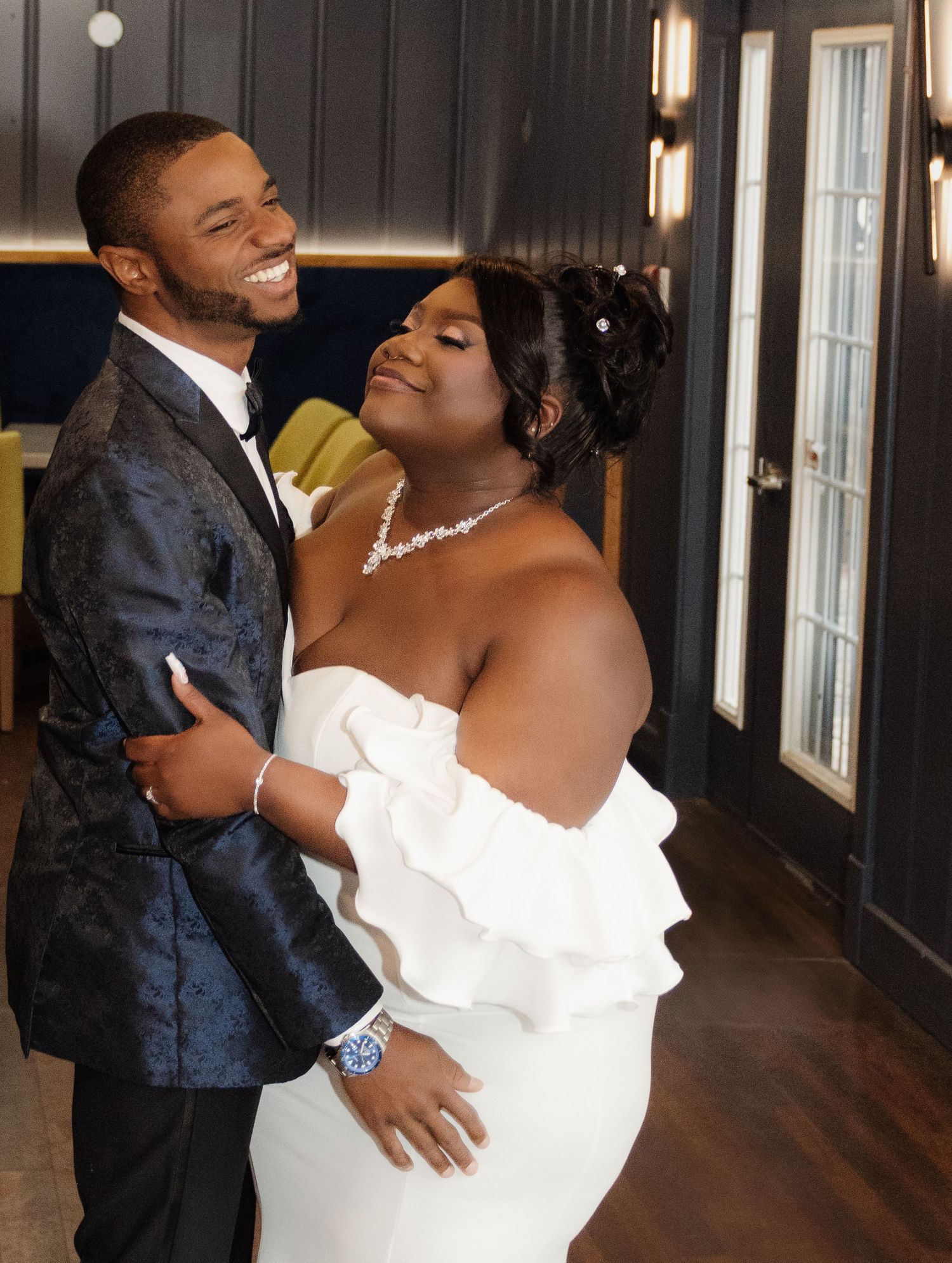 A joyful couple shares a romantic moment on their wedding day in a modern indoor setting.