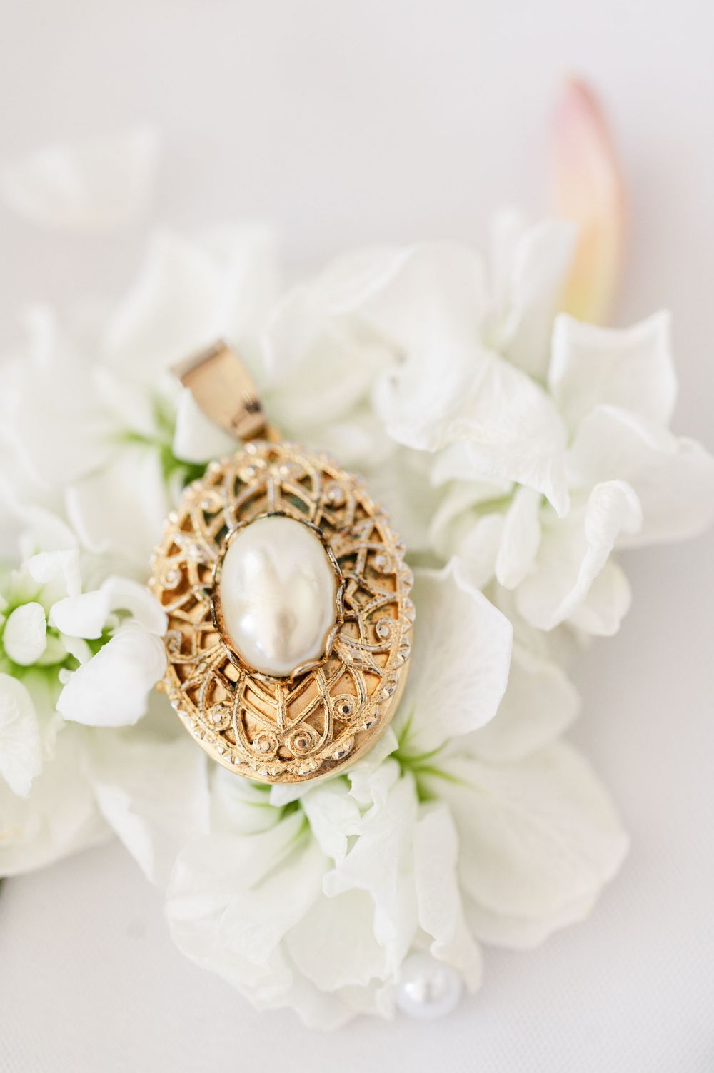Family heirloom brooch on white flower at wedding at OSU's St. John Catholic Student Center in Stillwater, Oklahoma.