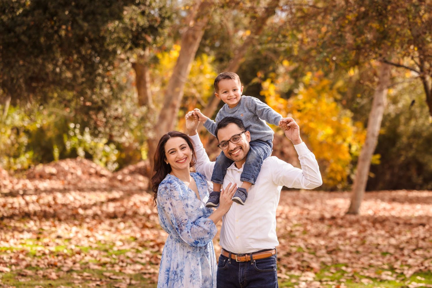 Happy family enjoying playful moment together in autumn park with golden light.
