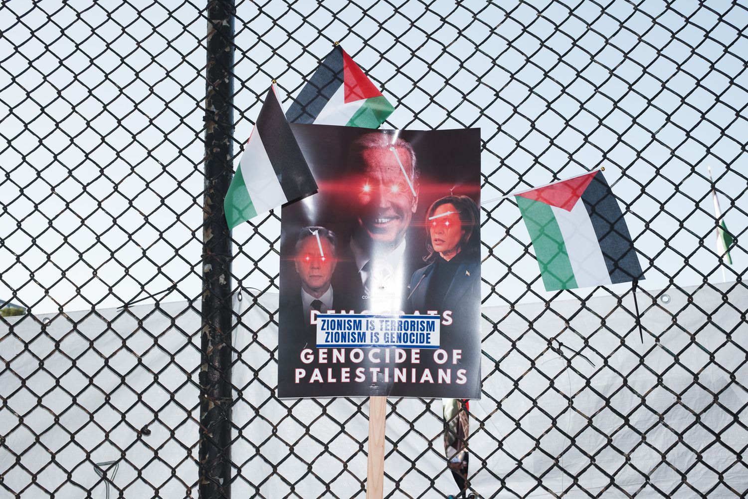 Palestinian flags and protest posters attached to a chain-link fence. Chicago. March on DNC