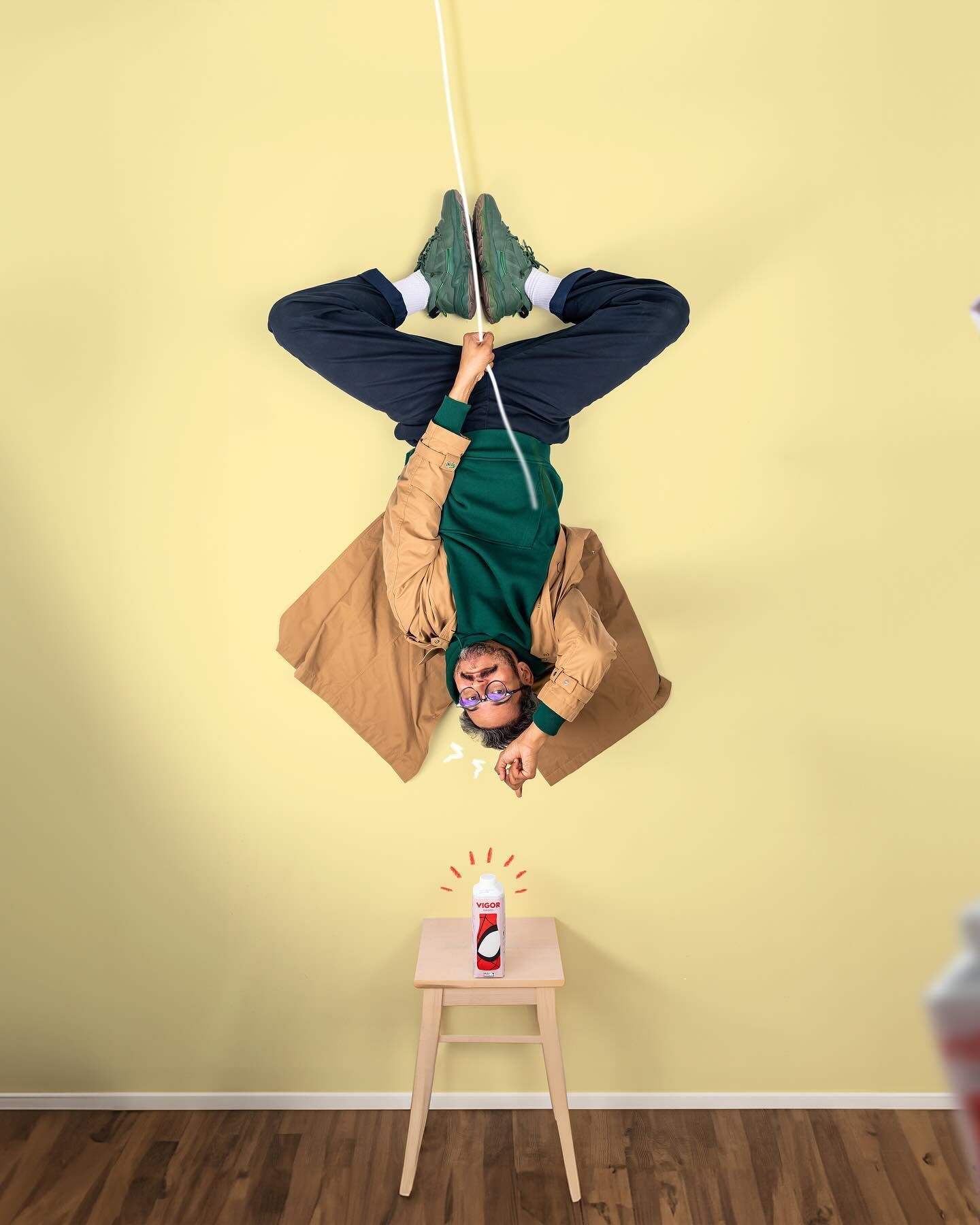 Creative composite photo showing someone hanging upside down over a small white wooden table with a candle on top.