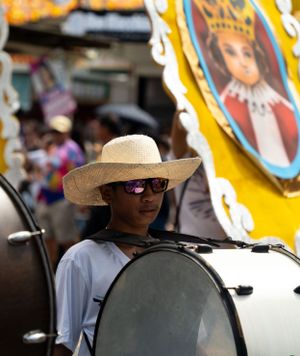 Festival performers wearing wide-brimmed straw hats against a backdrop of yellow banners.