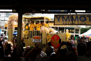 Night market scene with illuminated vendor stalls and crowds walking through an urban setting.