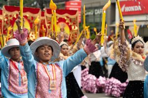 Colorful festival parade featuring dancers in traditional Filipino costumes with yellow and red banners.