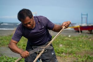 Group demonstrating traditional craft techniques outdoors near the ocean.