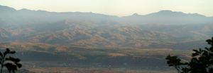Distant mountain ranges create a layered silhouette against the hazy sky.