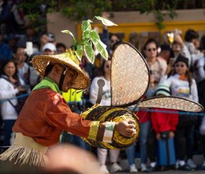 Traditional festival performers wearing straw hats and colorful costumes during a cultural celebration.