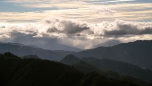 Misty mountain ranges at sunset with layered peaks fading into the horizon.