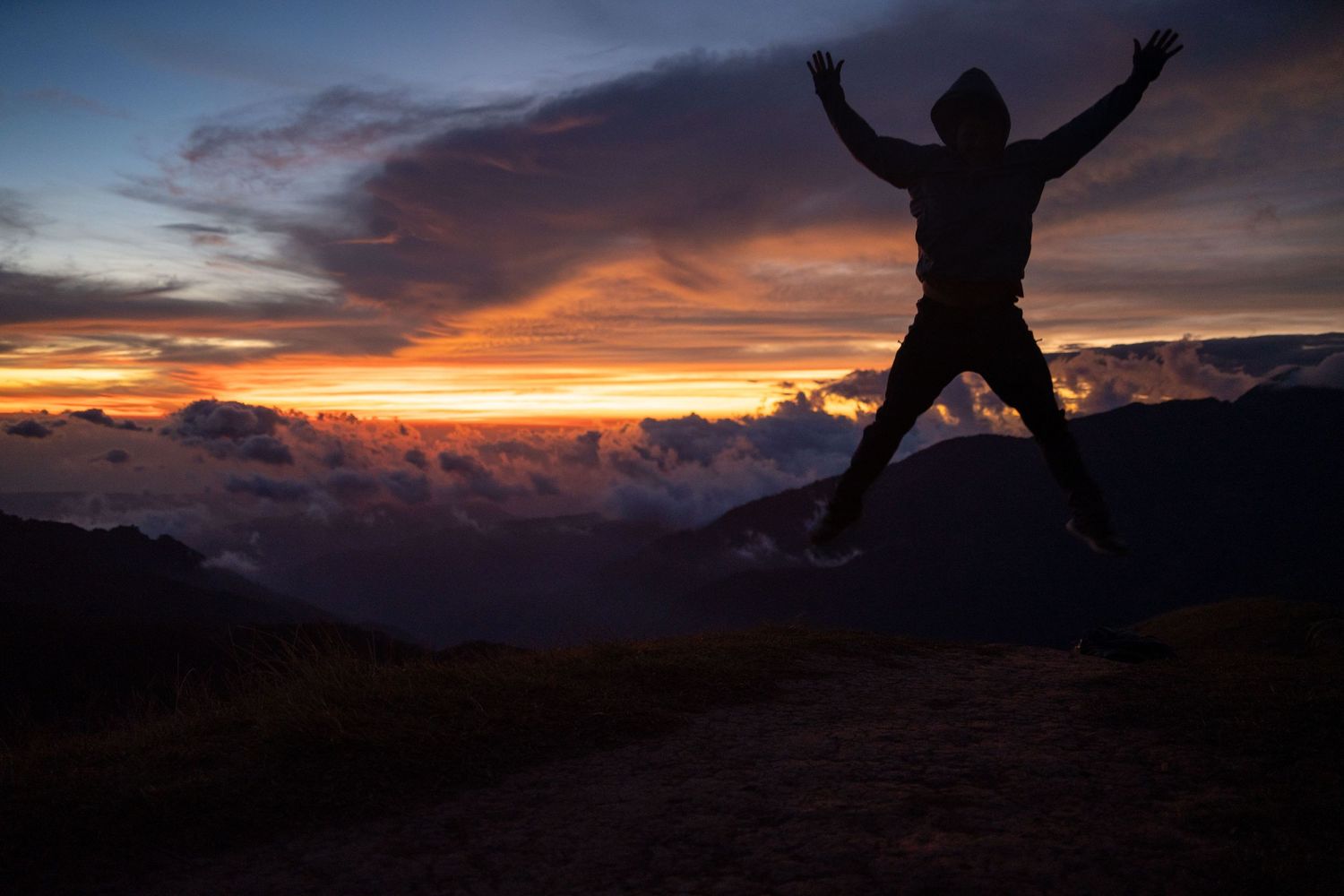 Dramatic sunset silhouettes of people jumping against a vibrant orange and purple sky.