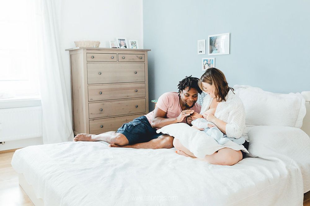 Zwei Kinder entspannen zusammen auf weißen Bettlaken und lesen Bücher in einem hellen Schlafzimmer mit blauen Wänden.