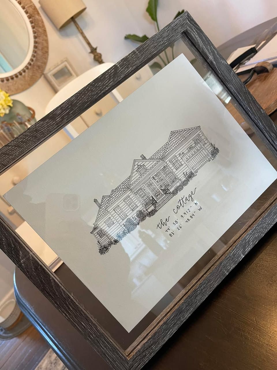 Framed architectural sketch of a detailed residential home in black and white.