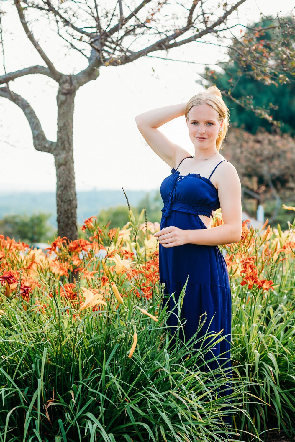 Portrait session in a garden with orange daylilies and a navy blue dress.
