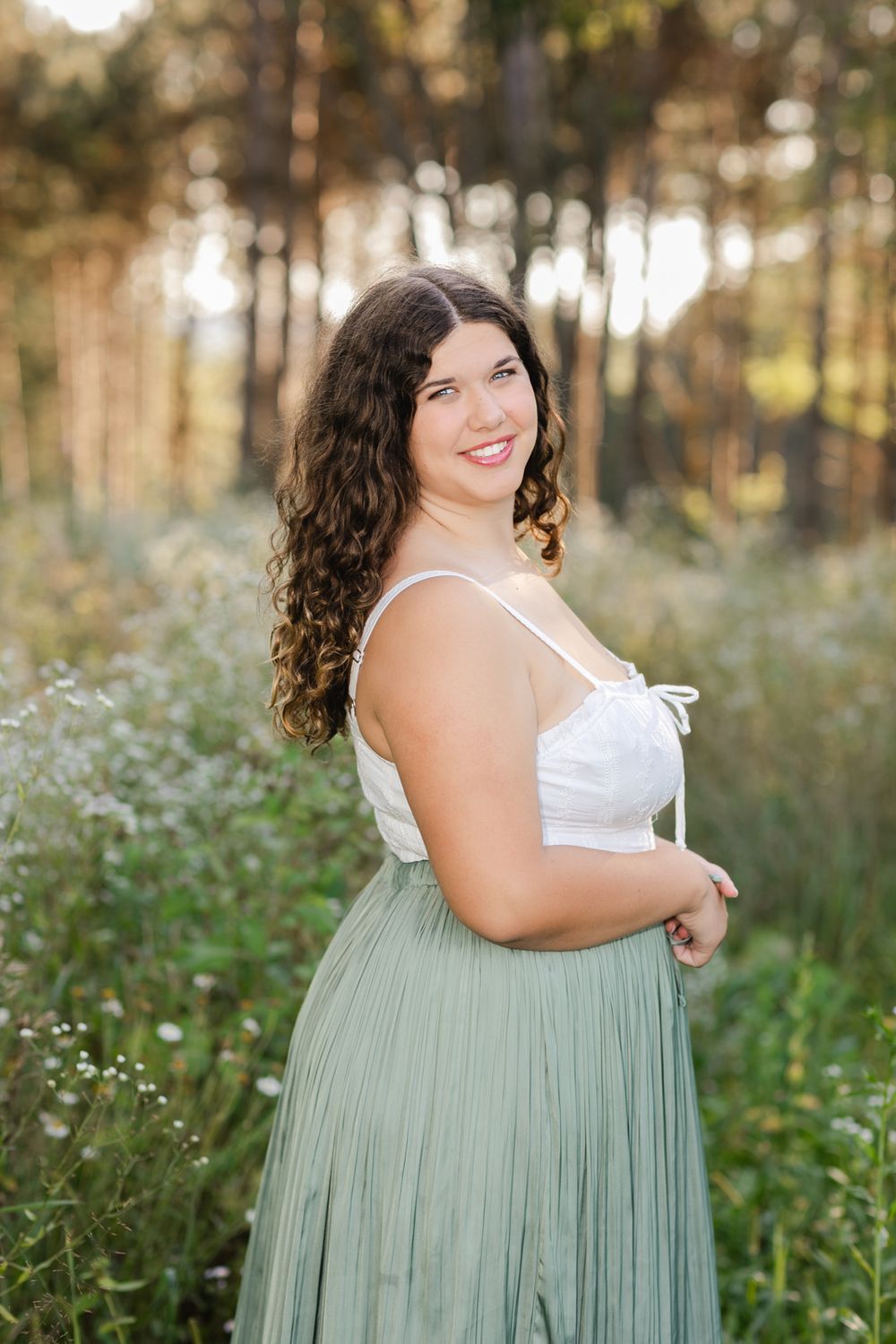 Summer portrait session among white wildflowers featuring a sage green flowing dress.