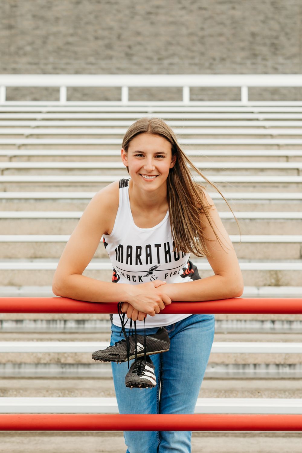 Athletic casual portrait on bleacher seating with red railing and concrete steps.