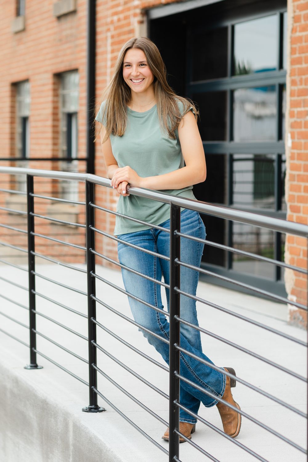 Casual outdoor portrait on white concrete steps with brick building and metal railing.