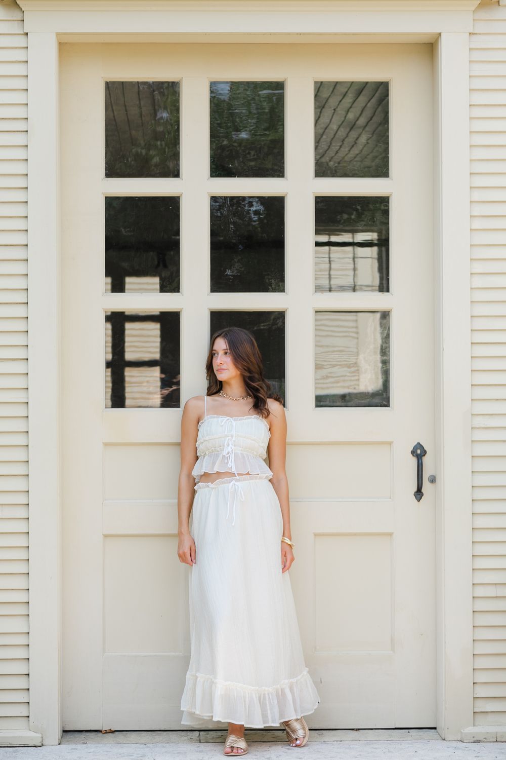 White dress portraits against a cream colored building with white doors.