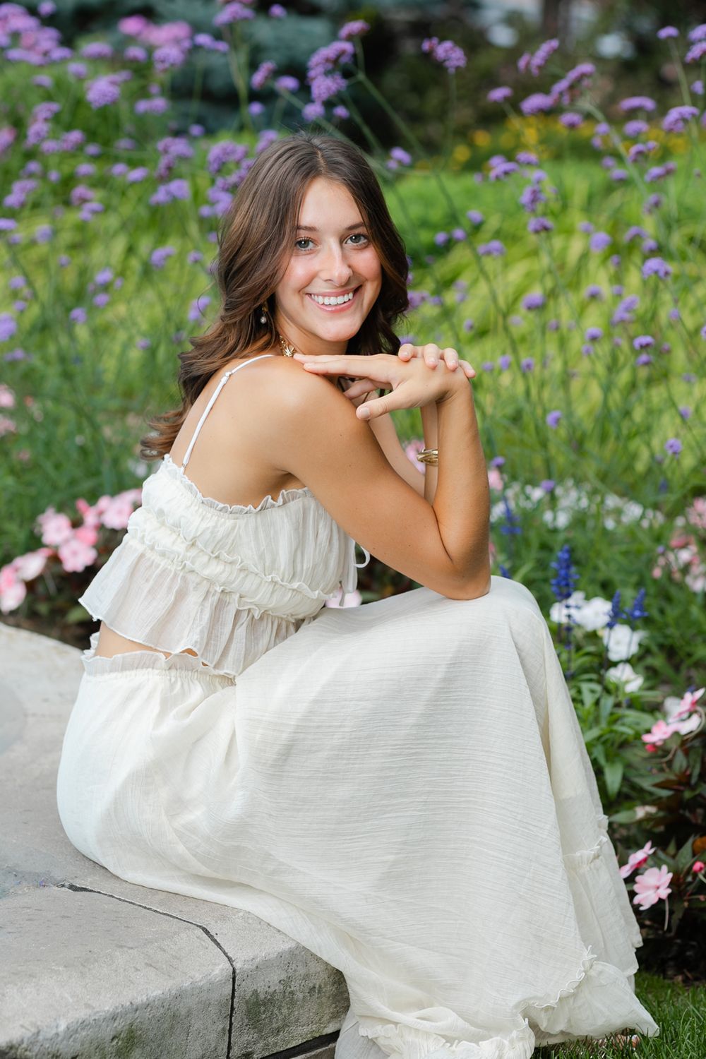 A white sundress photoshoot in a garden with pink and purple wildflowers.