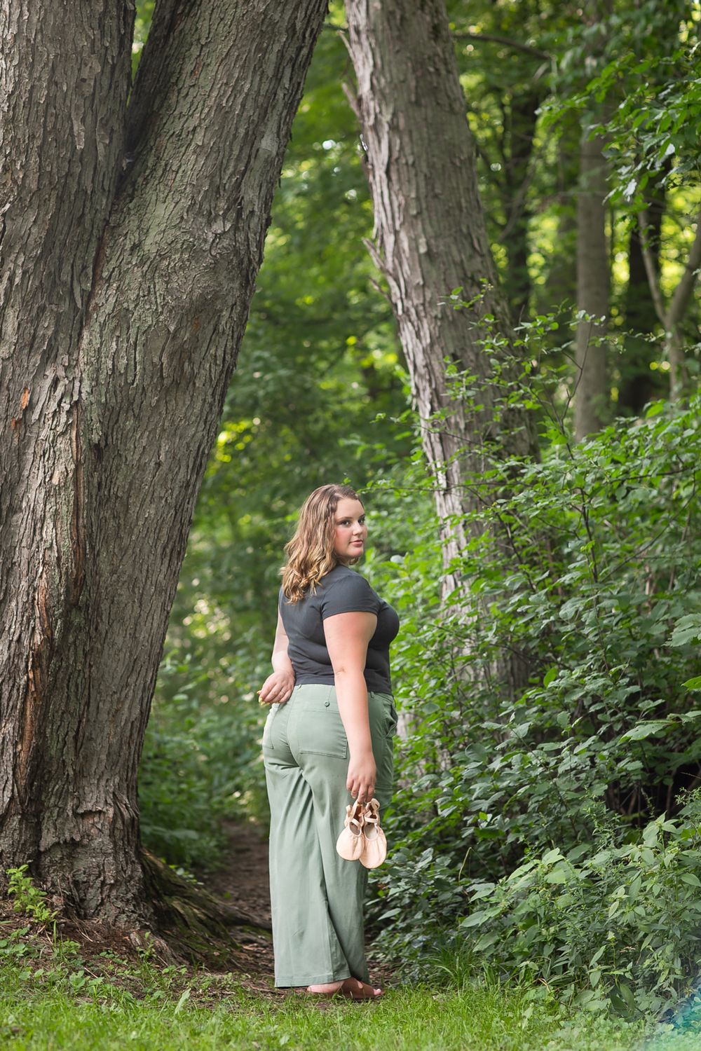 Natural outdoor portrait among tall trees in wooded setting.