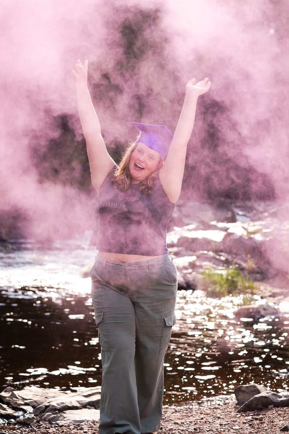 Creative portrait with pink smoke effects outdoors.