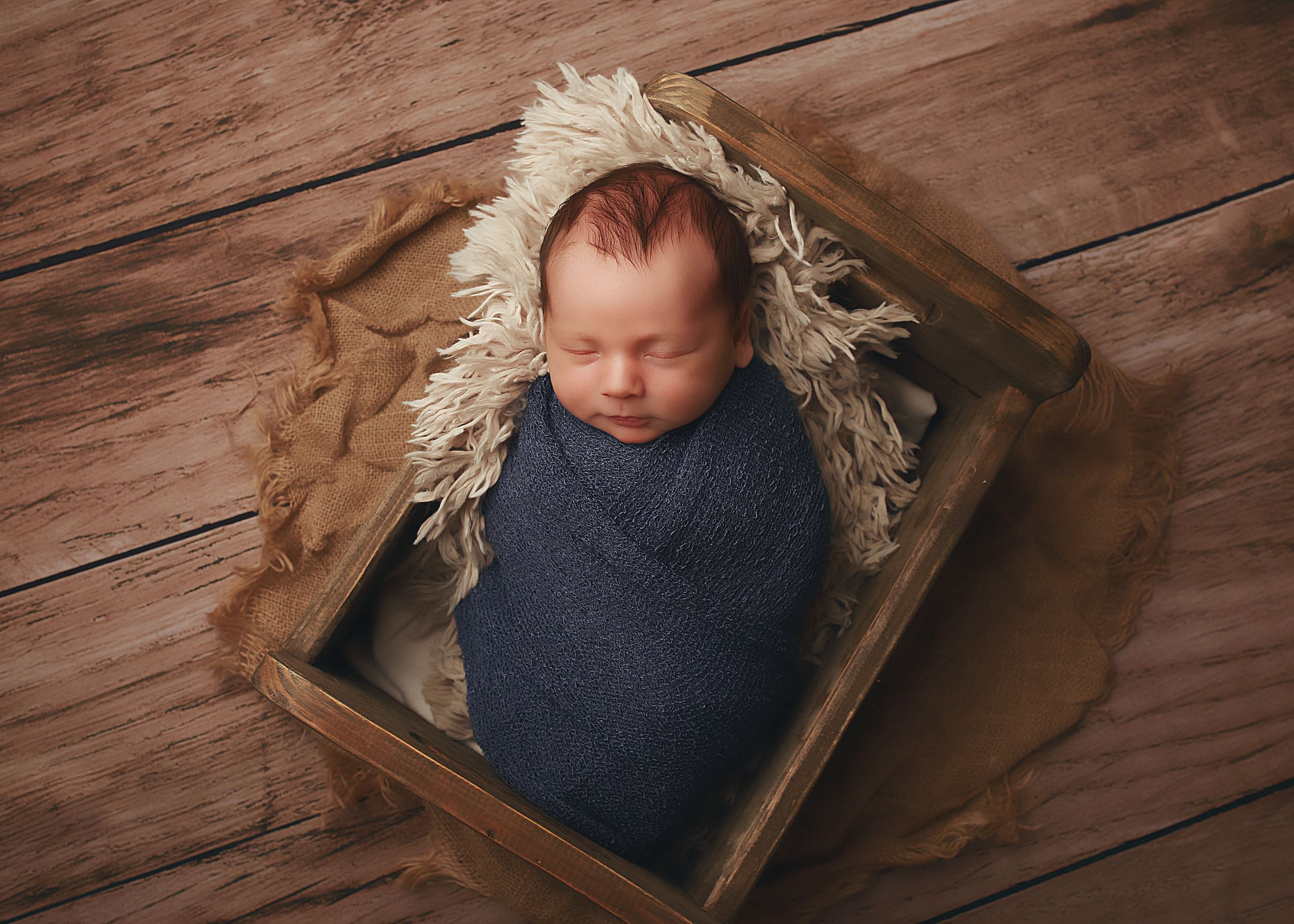 A peaceful newborn baby boy wrapped in soft fabrics, captured in a serene and intimate setting, showcasing the delicate beauty of early life