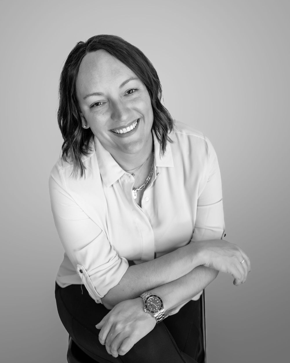 Black and white portrait of smiling woman in white blouse with watch.