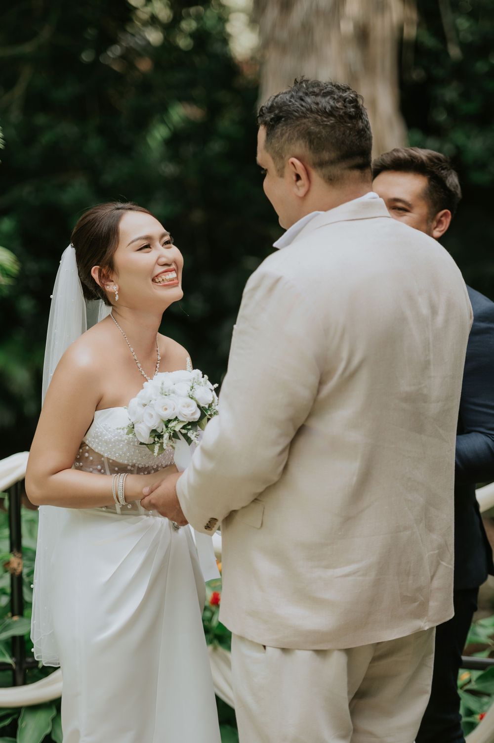 A beautiful outdoor wedding ceremony with joyful moments and white floral bouquet in a garden setting.