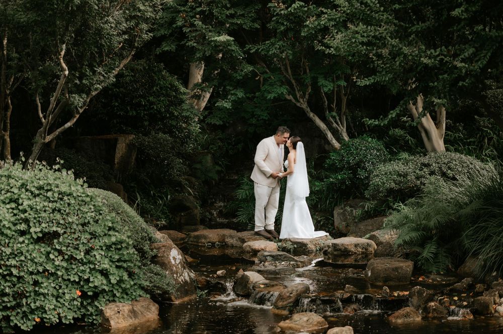 Romantic couple embracing on rocky stream in lush green forest setting during intimate outdoor moment.
