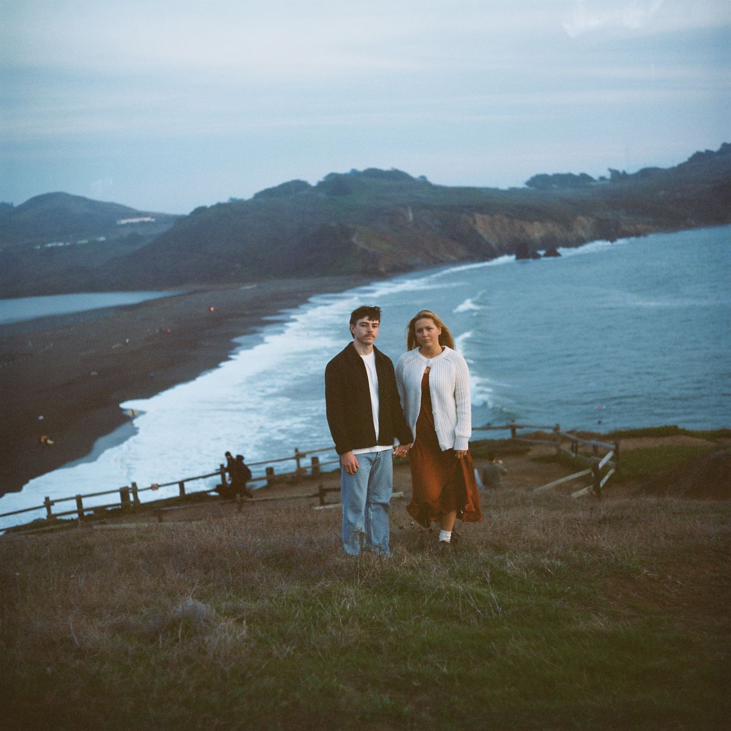 A couple poses on a cliffside over the beach in Northern California. Image is captured on the vibrant colors of Kodak's portra film stock