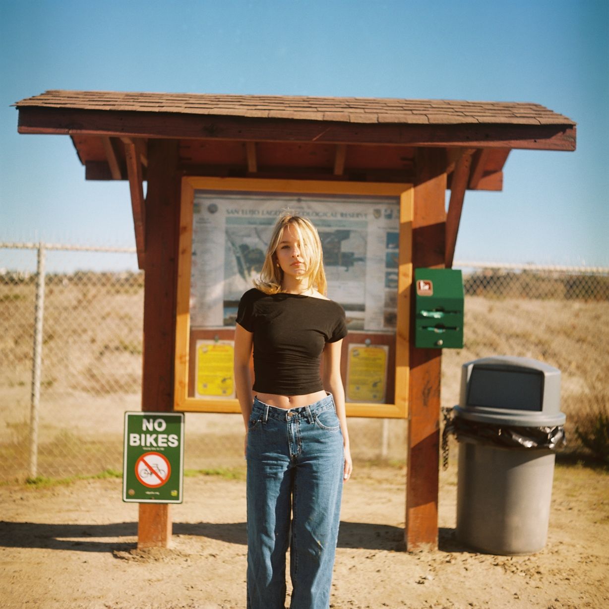 A female model poses in front of a trail sign. Image is captured on the vibrant colors of Kodak's portra film stock