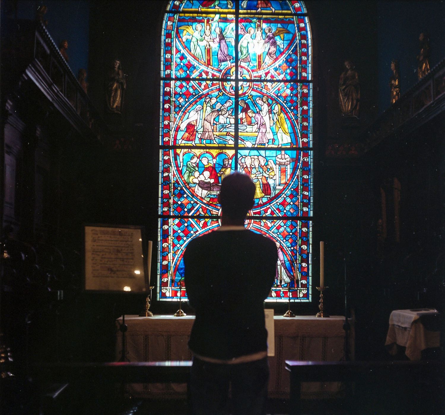 A male model poses in front of a large stained glass window at the Isabella Stewart Gardner Museum in Boston