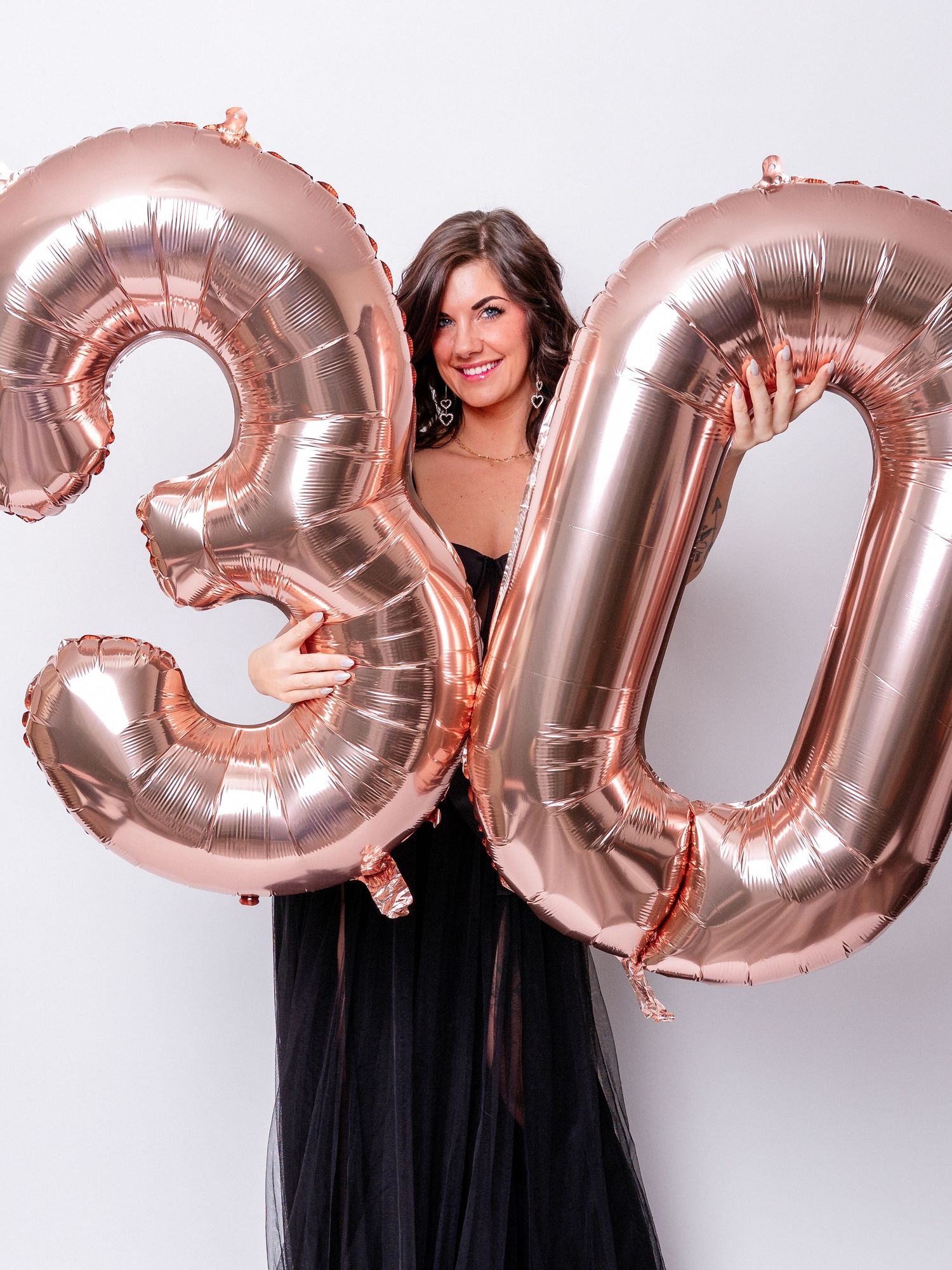 Photo of a beautiful woman in a black dress holding a 3 and a 0 for her birthday photo session. Photo was taken by portrait photographer.