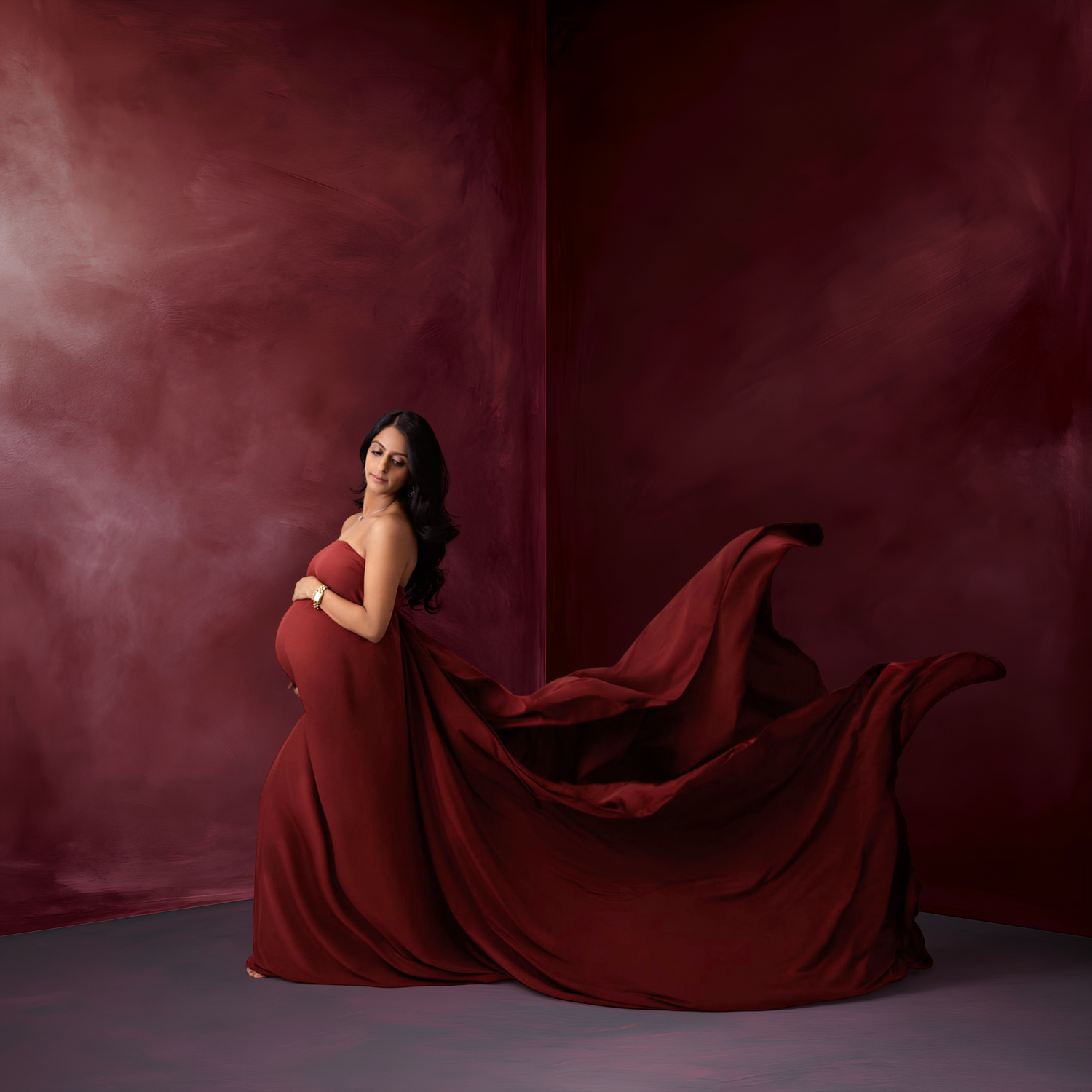 A maternity photo featuring an ethereal blue tulle gown with ruffled details against a textured backdrop.