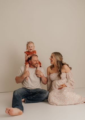 Family members playfully pose on the floor during a minimalist studio photography session.