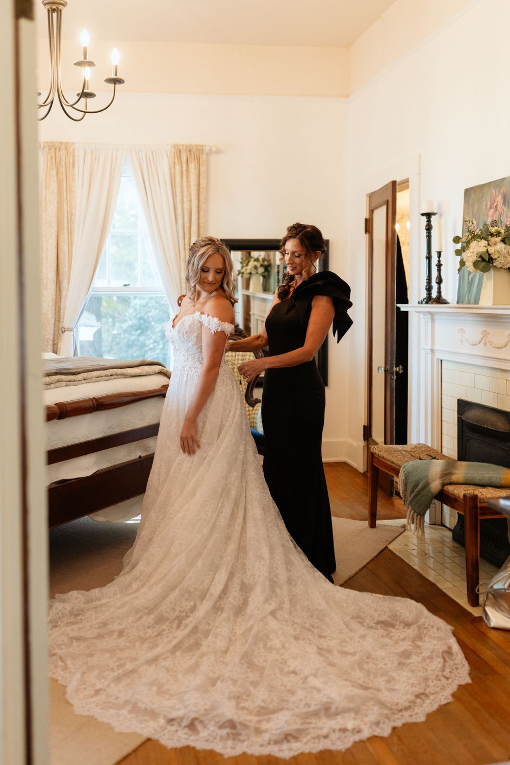 Photograph of a wedding dress fitting with long lace train in sunlit room at Wild Daisy Farm in Molena, Georgia.