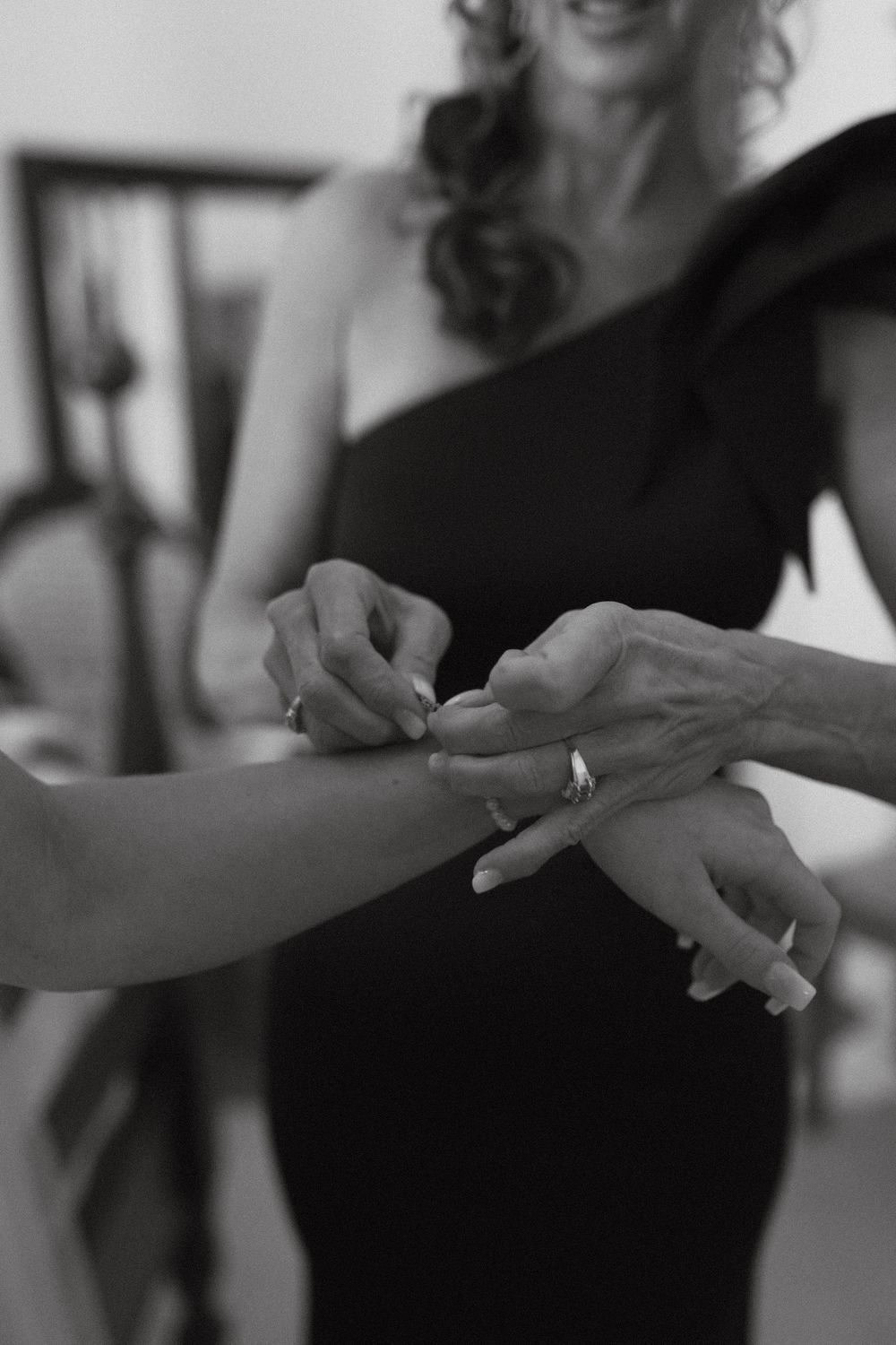 Photograph of a Close-up black and white shot of hands applying bracelet during wedding preparations at wild daisy farm in Molena, Georgia.