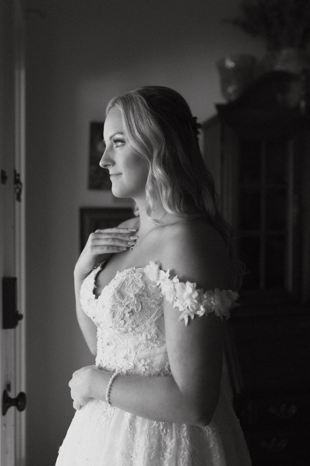 Photograph of a black and white portrait of bride in lace off-shoulder wedding dress at wild daisy farm in Molena, Georgia.