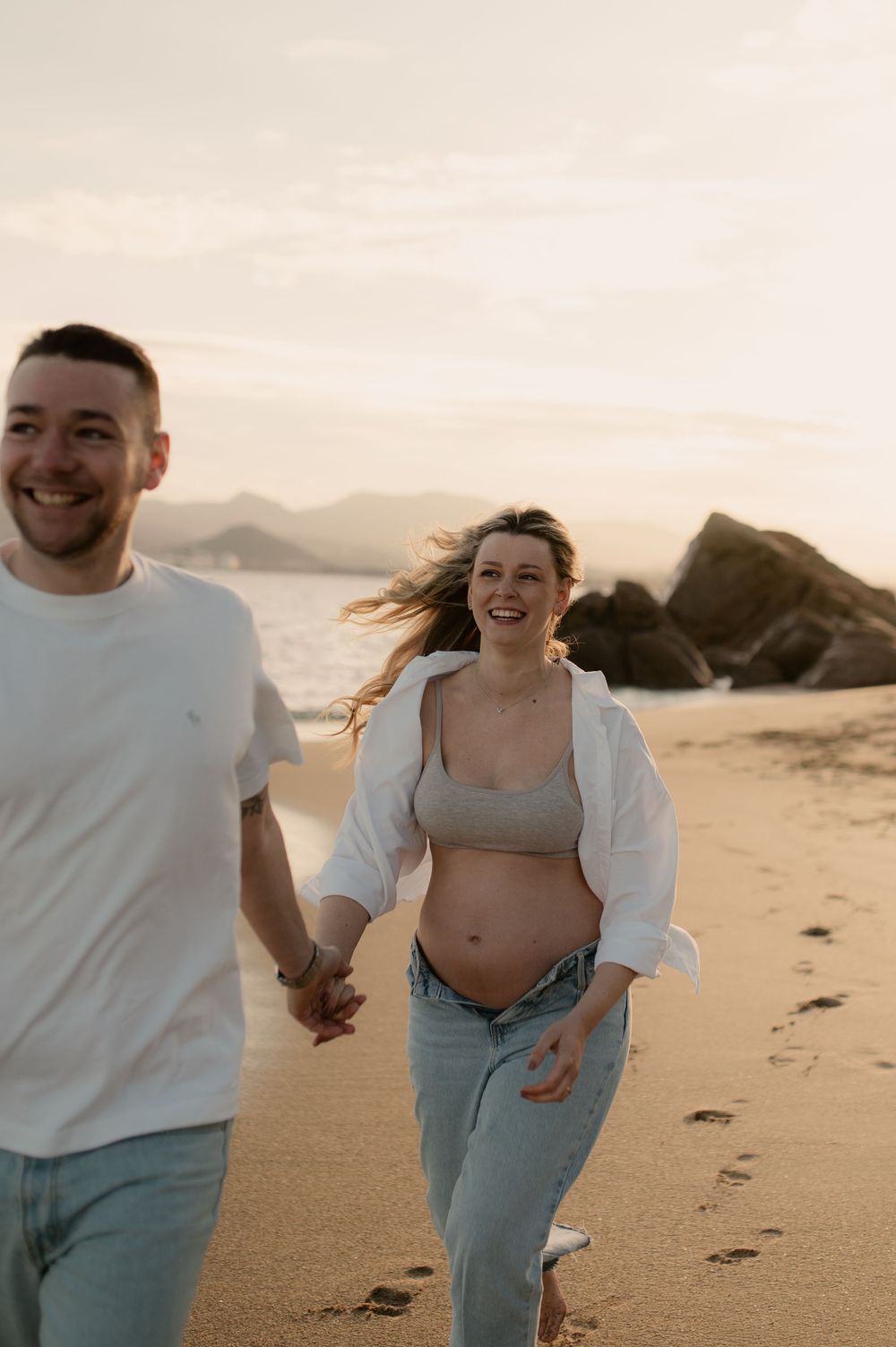 Séance maternité à la plage des rochers de Cannes la bocca - Homme qui tient la main de sa femme enceinte en marchant