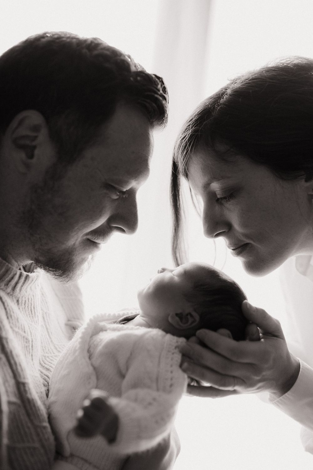 Portraits de profil de deux parents qui regardent leur nouveau né lors d'une séance photo naissance à Carros