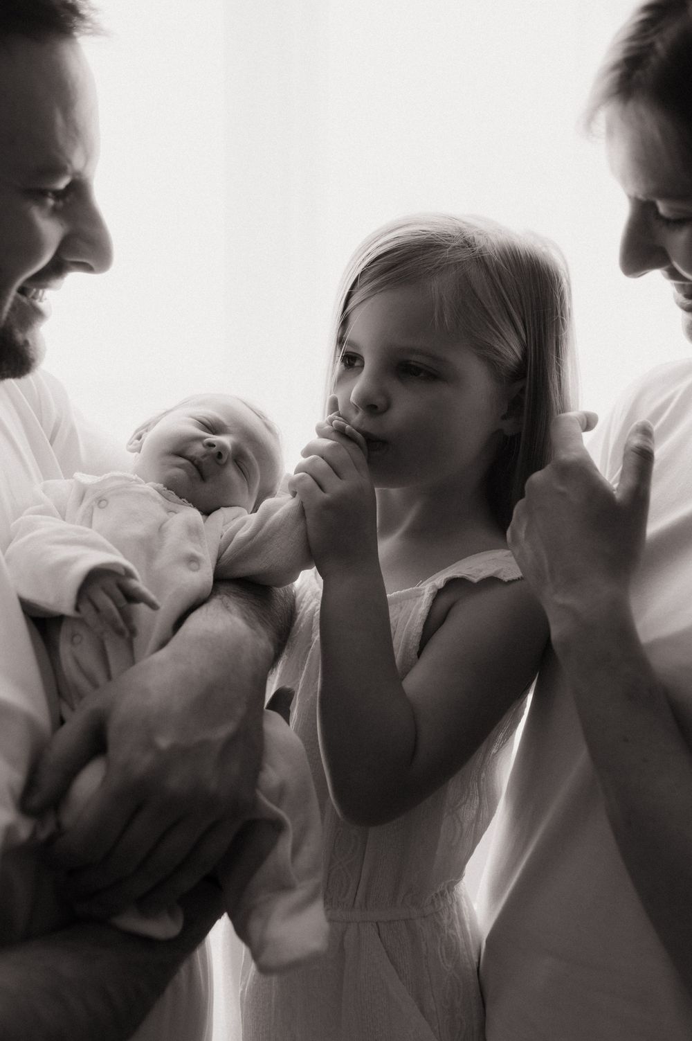 Séance naissance à domicile Alpes maritimes - Gros plan d'une petite fille qui embrasse la main de sa petite soeur qui vient de naitre