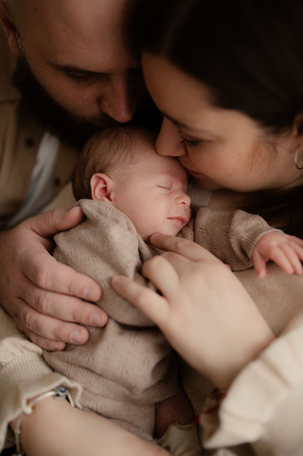 Photographe naissance à Saint Laurent du var - Parents qui embrassent leur nouveau né qui sourit.