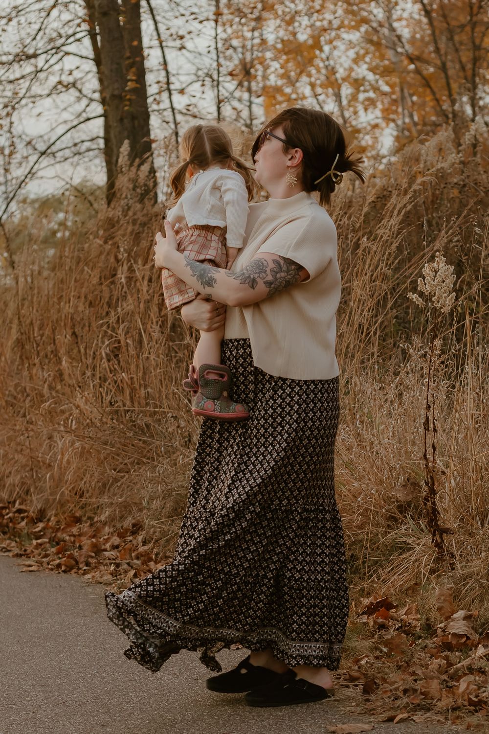 A tender autumn moment on a path surrounded by golden grass and fall foliage.