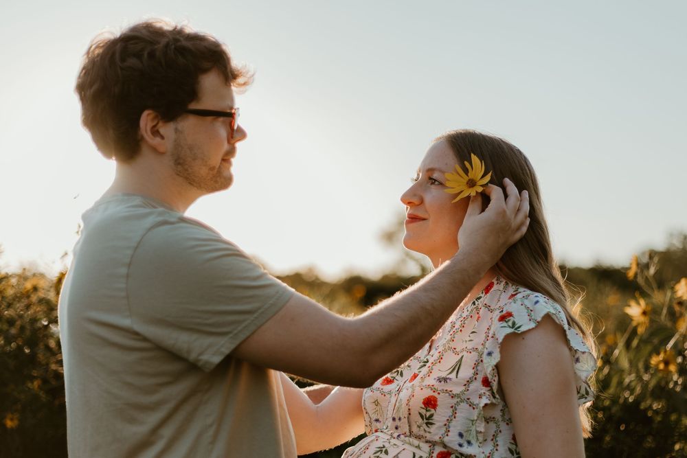 Romantic couple sharing intimate moments in a sunlit field during golden hour sunset.